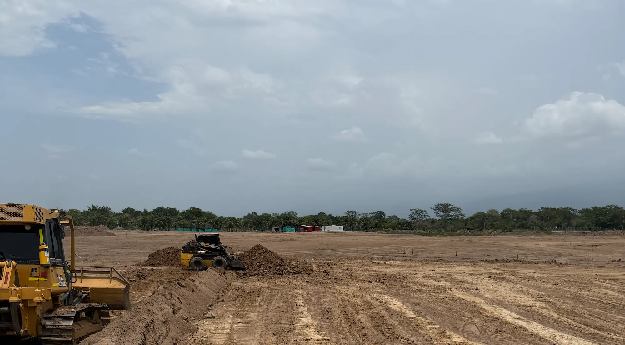 Lote en movimiento de tierra con bulldozer y minicargador nivelando el terreno